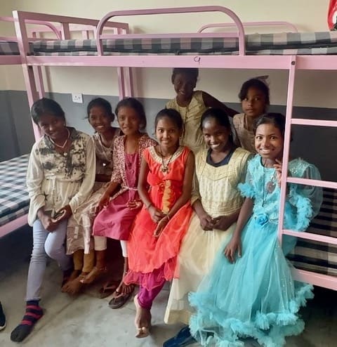 Lakshmi, the young girl at the center of the Lakshmi leprosy miracle, sits joyfully with friends at Rising Star Outreach in India, where she found love, care, and education after being abandoned due to leprosy.