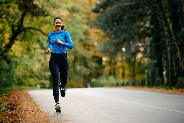 A woman jogs on a forest road, representing regular exercise—an essential part of maintaining metabolic health and achieving weight loss goals.