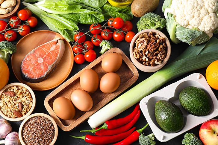 A variety of nutrient-dense foods—fish, eggs, avocados, and vegetables—illustrating the healthy diet principles supported by HLTH Code Complete Meal.