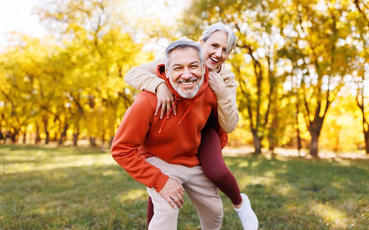 A joyful middle-aged couple enjoying an active lifestyle outdoors, symbolizing the healthy weight management and energy benefits promoted by HLTH Code Complete Meal.