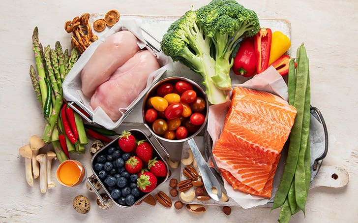 Fresh salmon, vegetables, and berries displayed to emphasize proper macros for metabolism health and healthy weight management like HLTH Code supports.
