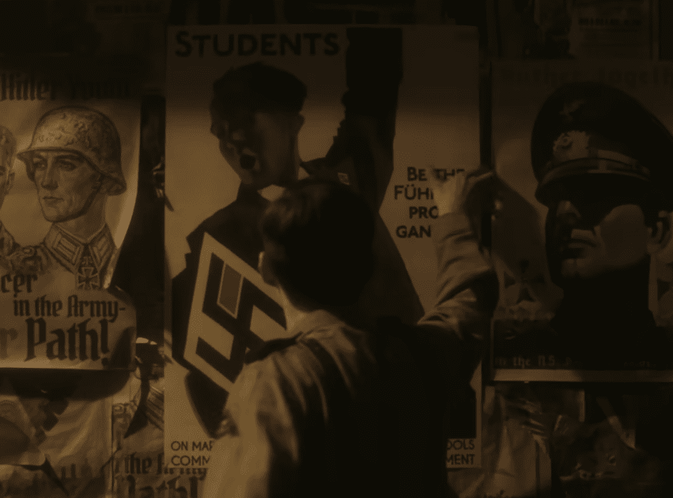A dramatic scene from Truth or Treason Angel Studios movie as Helmuth Hubener posts anti-Nazi leaflets over propaganda posters, symbolizing his fearless stand for truth.
