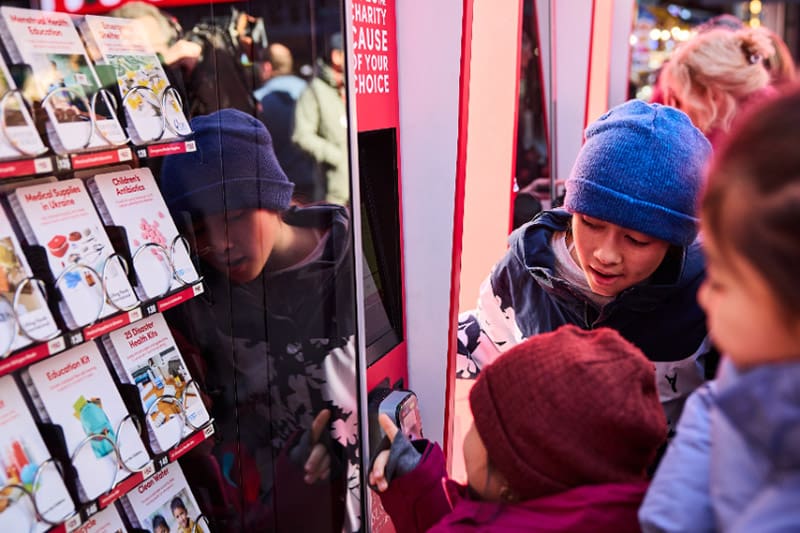 Children choosing charitable gifts at a Light the World Giving Machine to honor Jesus Christ and help those in need worldwide.