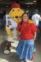 A joyful young woman with Down Syndrome smiles as she poses at a baseball stadium with the team mascot. This photo of Grace Schara captures her vibrant personality and happy moments shortly before her wrongful death case drew national attention.