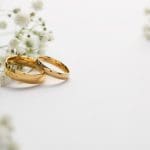 Gold wedding rings with white flowers symbolizing eternal union and God’s law of marriage in the new and everlasting covenant.