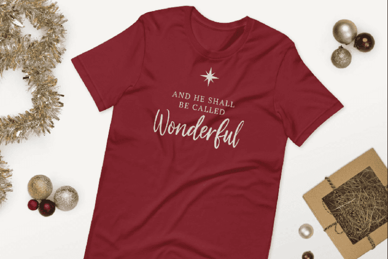 Red Christmas T-shirt reading “And He Shall Be Called Wonderful” displayed with holiday décor, part of the uplifting Christian Christmas apparel collection.