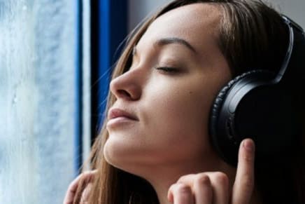 Woman wearing headphones, symbolizing listening to personalized Gospel Library app playlists for worship and study.