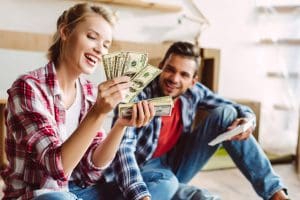 Woman counting money while man watches, symbolizing dating a gold digger and financial motives in middle-age relationships.