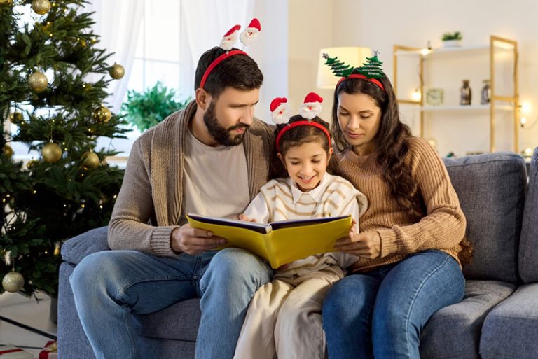 Family reading Christmas children’s books together, enjoying Christmas picture books and a meaningful Christmas read-aloud about faith and the true meaning of Christmas.