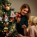 Mother and child decorating a Christmas tree, symbolizing the spirit of Christmas found through Jesus Christ, peace, gratitude, and simple acts of love.