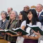Latter-day Saint congregation singing hymns together, showing how sacred Christmas music invites the Spirit and brings peace.