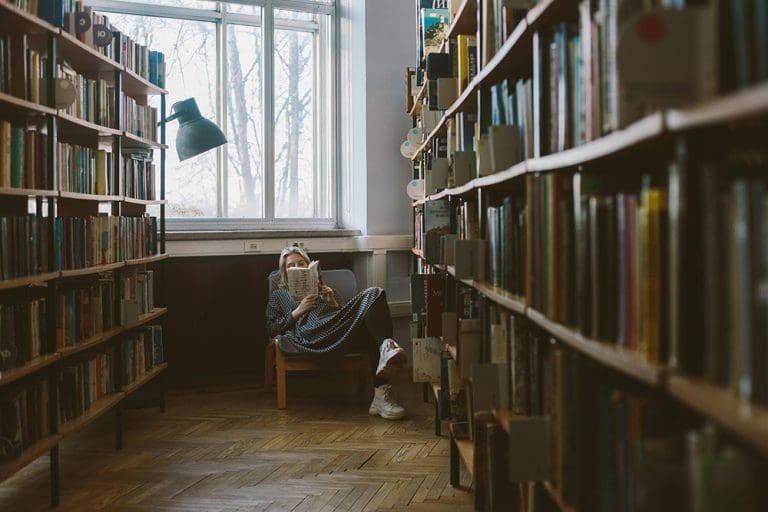 Child reading books in a library during winter, reflecting cozy winter books and picture book reading for children.