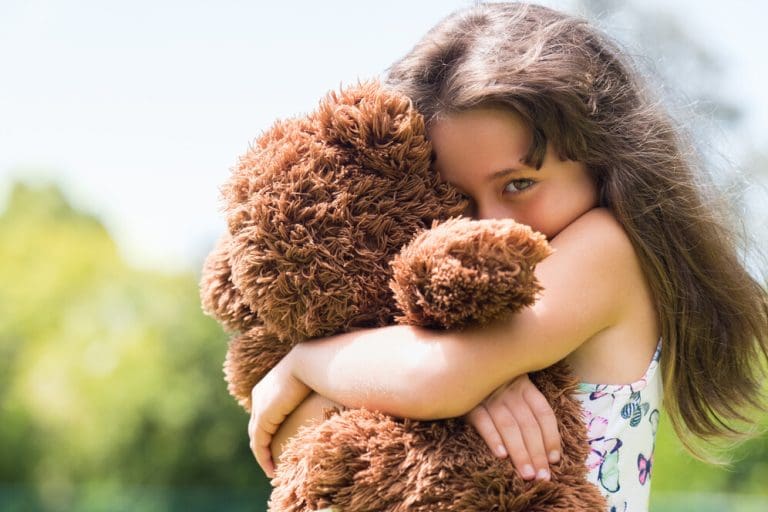 girl in foster care hugging a teddy bear in a loving foster family setting