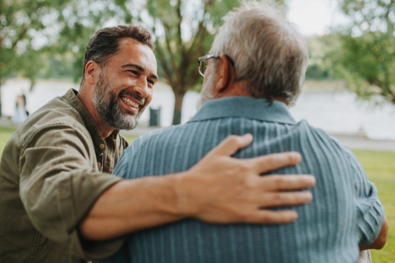 Two men share a supportive embrace, representing family unity built through forgiveness, respect, and Christlike love despite differences.