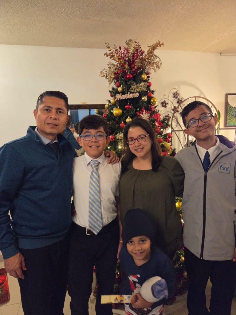 A family stands together in their home during the Christmas season, representing how the Perpetual Education Fund strengthens families through education, employment, and self-reliance worldwide.