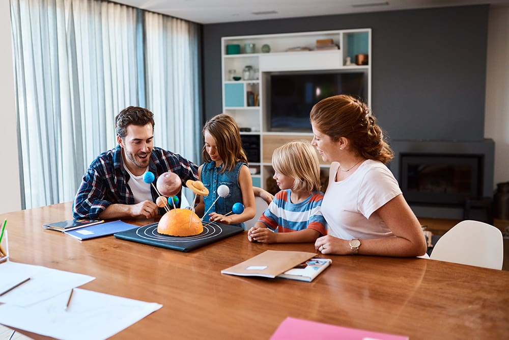 Parents teaching children at home with a science project, modeling godly parenting, compassion in parenting, and foundational principles of parenting centered on God.