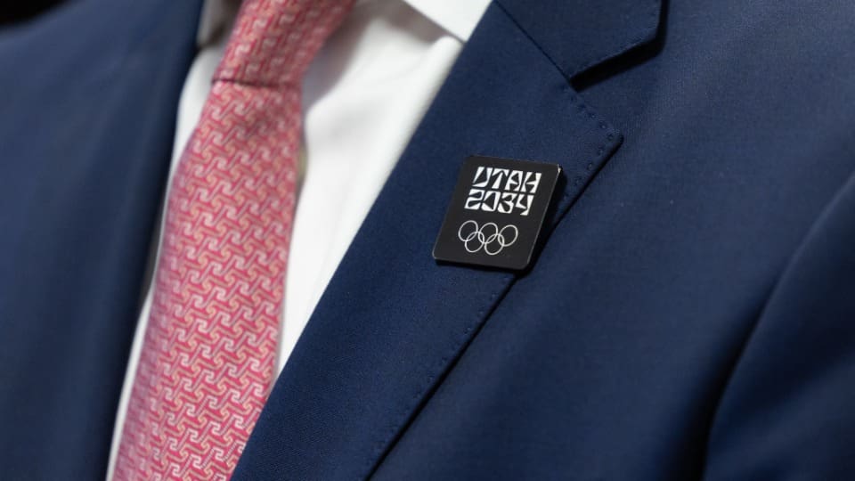 A close-up of a Utah 2034 Olympic pin worn during the Milan media announcement symbolizing the upcoming Winter Games in Salt Lake City