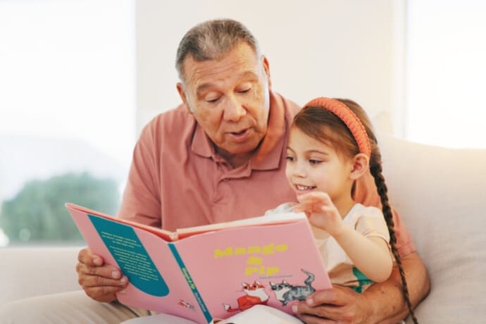 Grandfather reading Valentine’s Day picture book with granddaughter, sharing love and friendship through children’s books.