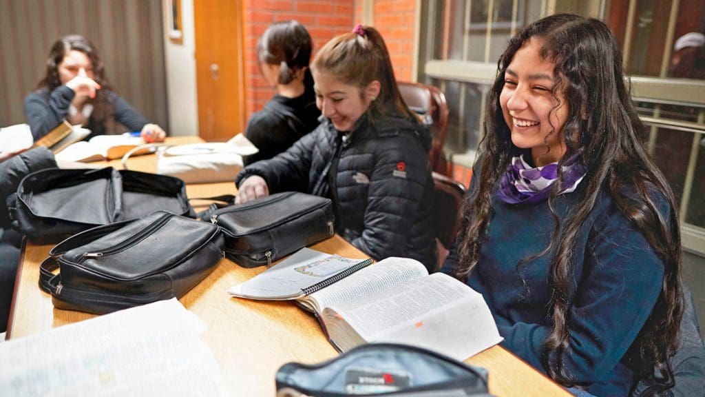 Young women study scriptures together in an Institute setting, illustrating the impact of Institute classes on youth and young adults