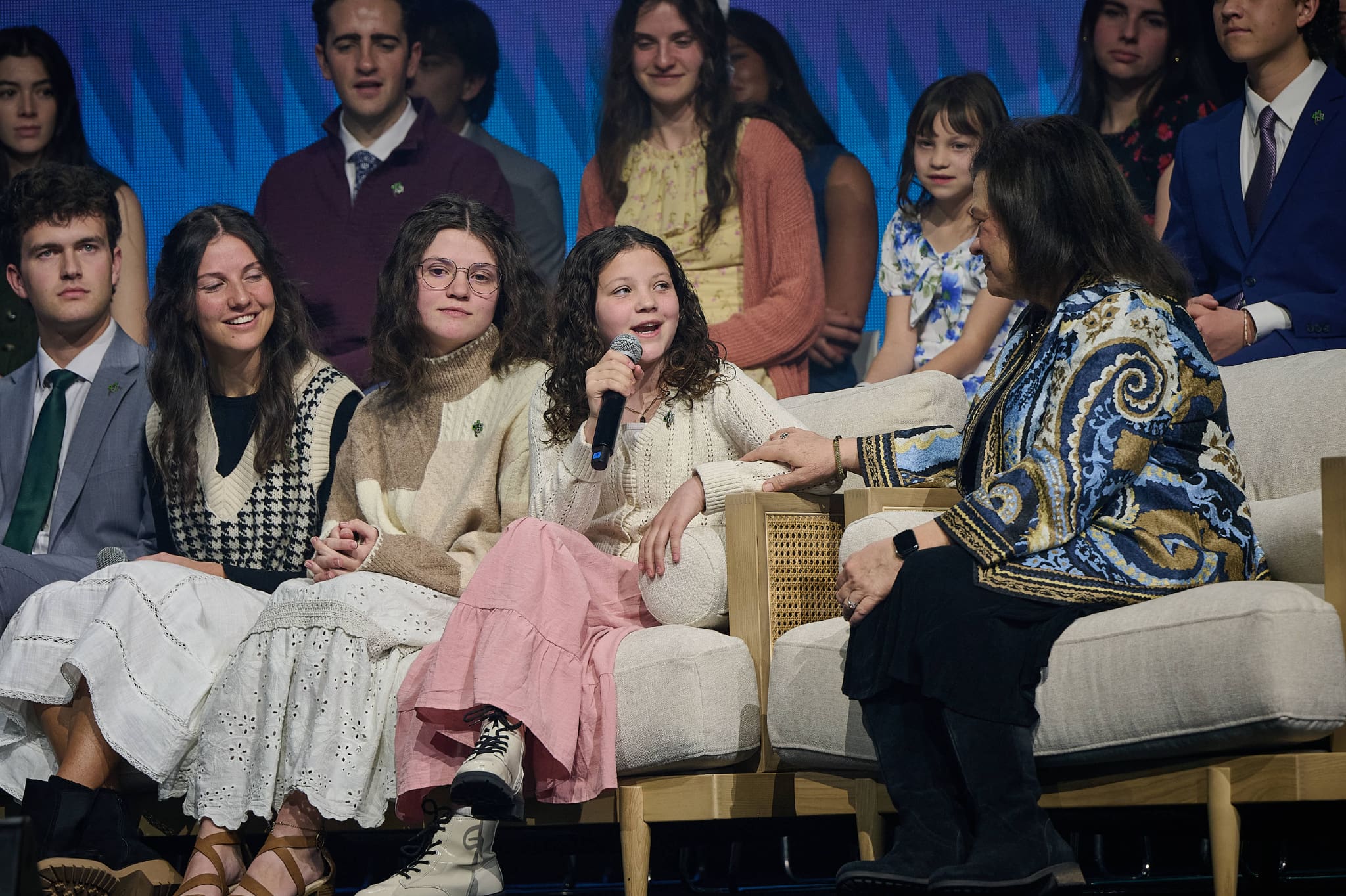 Sister Melanie Rasband sits with young audience members and grandchildren during Family Discovery Day at RootsTech 2026, discussing family history and how faith from ancestors strengthens today’s families.