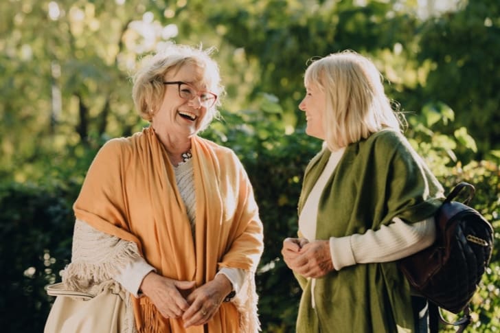 Two women using strong communication skills with positive body language and tone of voice in conversation.