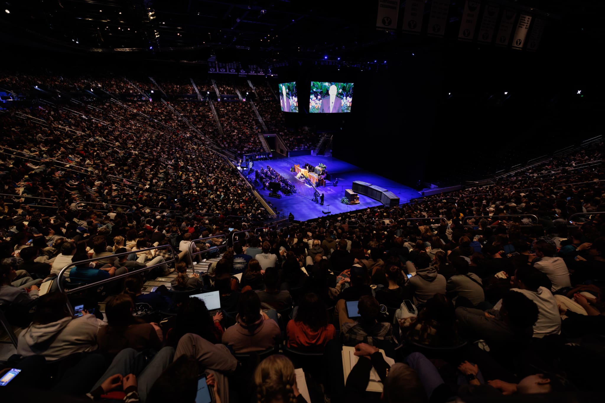 A wide view of the Marriott Center at Brigham Young University filled with thousands of BYU students gathered for a devotional where Elder Quentin L. Cook taught about discipleship, technology, and the challenges of the artificial intelligence age.