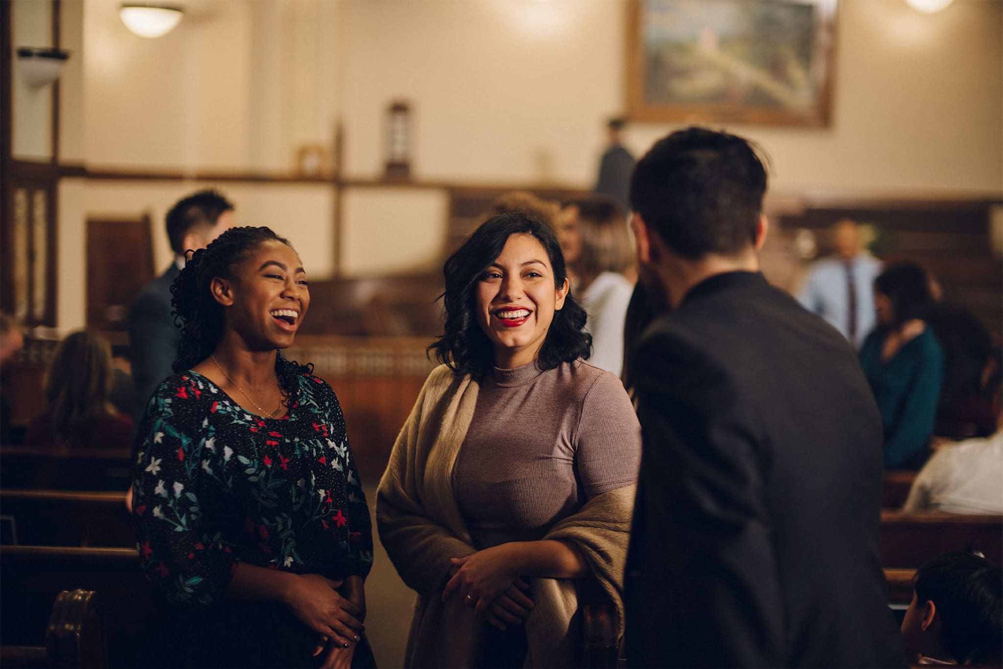 Members of The Church of Jesus Christ of Latter-day Saints gather and visit inside a chapel, reflecting fellowship and connection during Sunday meetings.