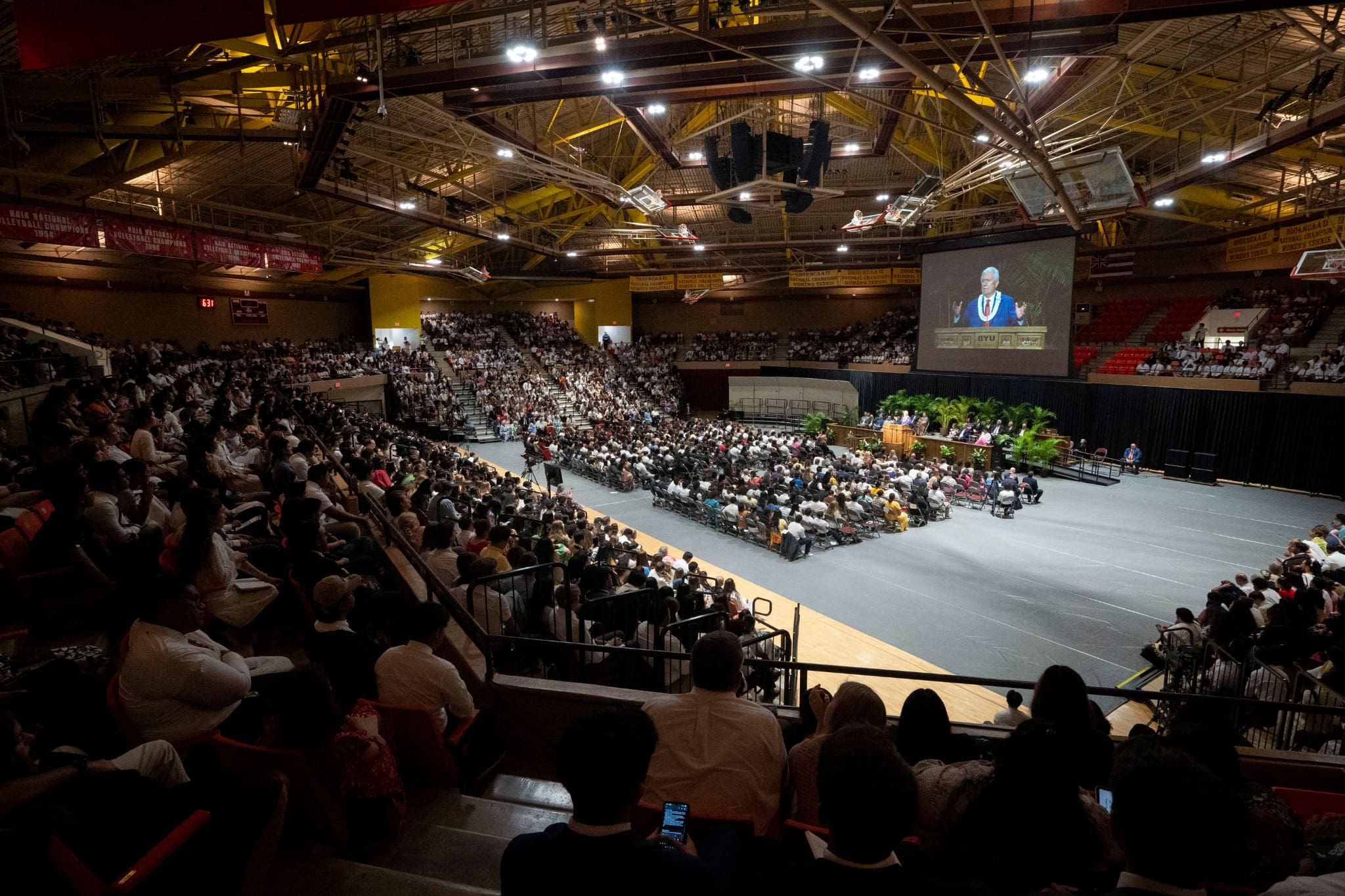 A large gathering of students and members fills the Cannon Activities Center at BYU–Hawaii during a devotional where President Dieter F. Uchtdorf encourages young Latter-day Saints to stand together in unity and discipleship.