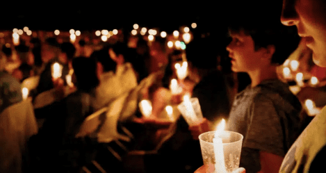 People holding candles during a worship service, representing reverent gatherings during Holy Week that focus on the sacrifice and Resurrection of Jesus Christ.