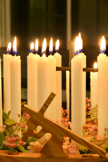Lit candles beside a wooden cross representing reflection, prayer, and worship during Holy Week as believers remember Christ’s sacrifice and anticipate the joy of Easter.