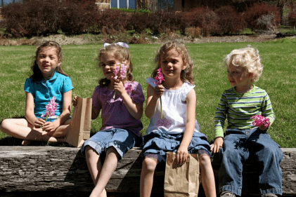 Children holding spring flowers outdoors, representing the joy of the Easter season and the new life symbolized by the Resurrection of Jesus Christ.