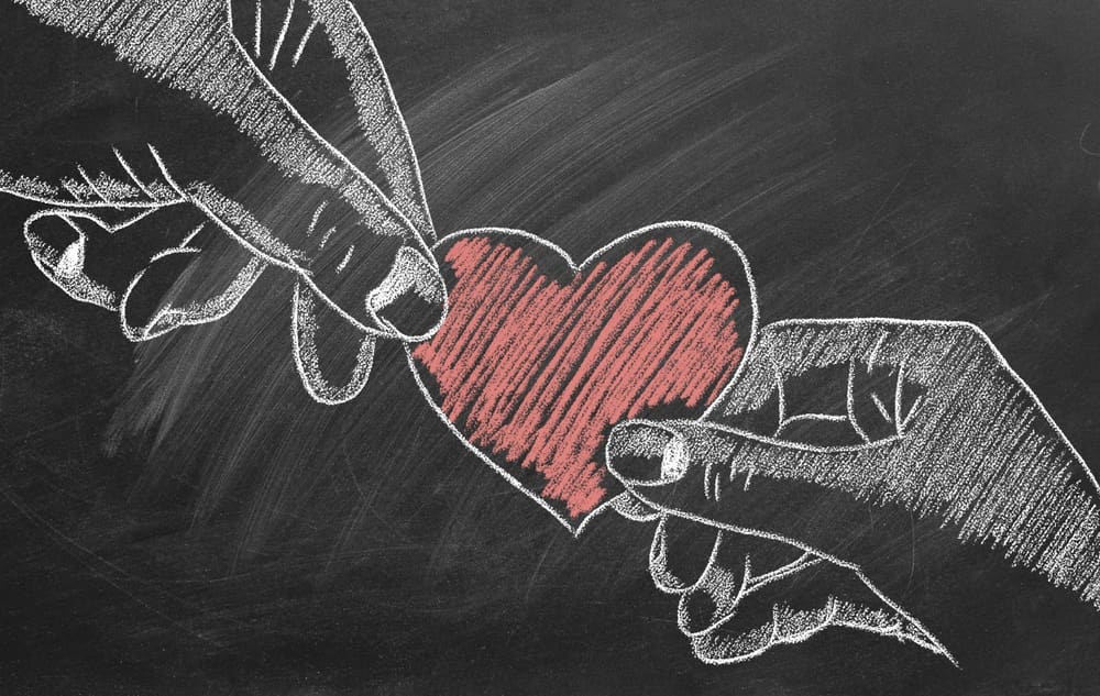Hands passing a heart symbolizing compassion in parenting, Christlike love, and the example of the Good Samaritan in caring for others.