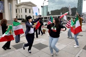 Protesters waving Iranian flags at a demonstration supporting democracy in Iran and human rights for Iranians.