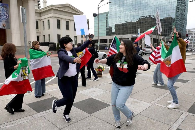 Protesters waving Iranian flags at a demonstration supporting democracy in Iran and human rights for Iranians.