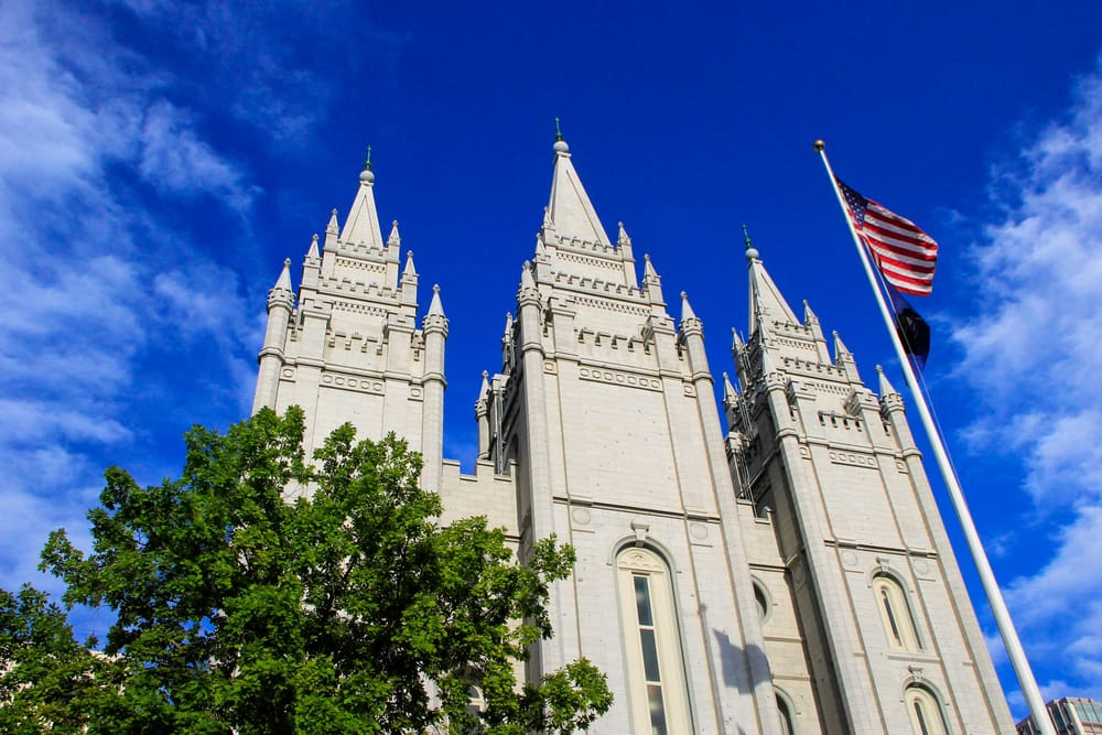 The Salt Lake Temple of The Church of Jesus Christ of Latter-day Saints with the American flag flying nearby, symbolizing the Church’s emphasis on religious liberty and the First Presidency’s invitation to fast during the Declaration of Independence 250th anniversary.