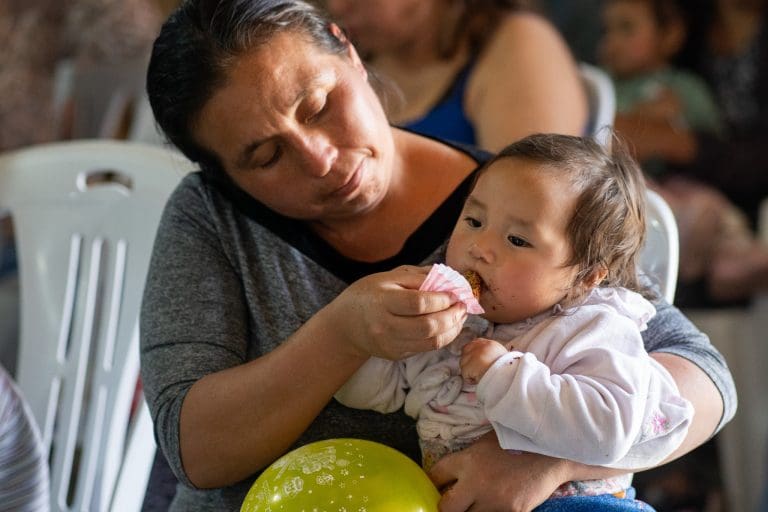 Mother feeding child during humanitarian aid supported by The Church of Jesus Christ of Latter-day Saints Caring for Those in Need 2025 Report