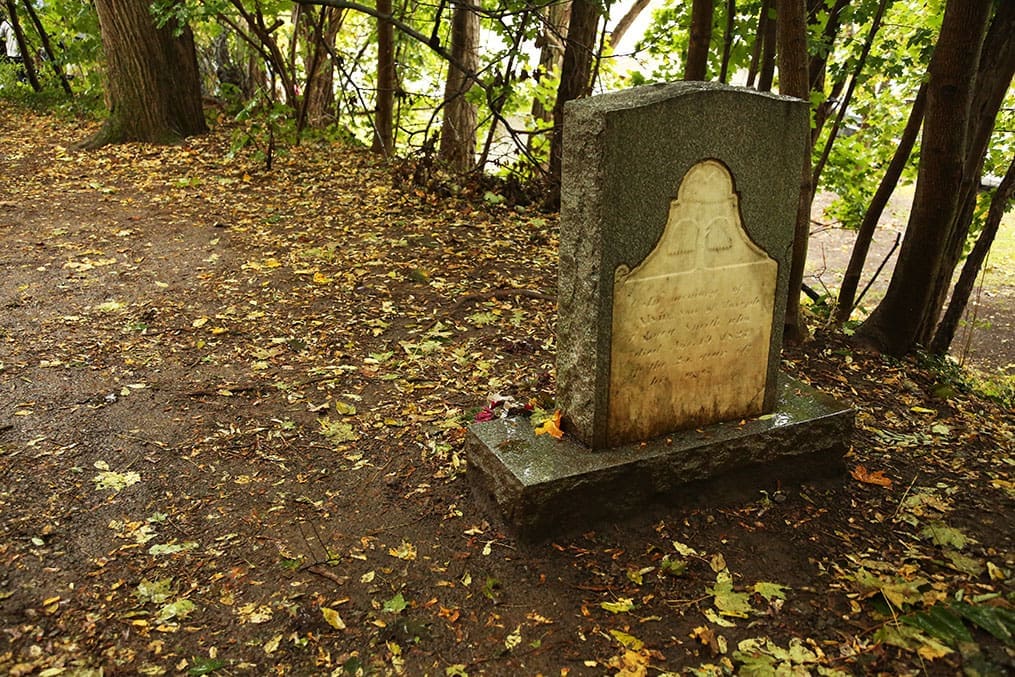 A quiet grave marker for Alvin Smith in a wooded setting near Palmyra, visited on the Church History tour as part of Joseph Smith family history and Sacred Grove experiences.
