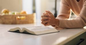 Person praying over scriptures illustrating Study Pray Obey Joseph Smith obedience to God Atonement of Jesus Christ