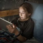 child using device alone representing outsourcing of parenting and reduced parental involvement in child development