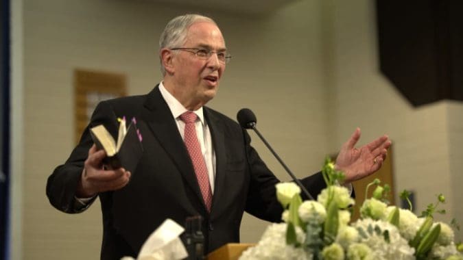 Church leader speaking at a pulpit, teaching about Jesus Christ and encouraging discipleship among members.