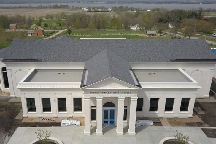 Exterior view of the newly completed Nauvoo Temple Visitors’ Center in Illinois, highlighting ongoing temple announcements and Church growth.