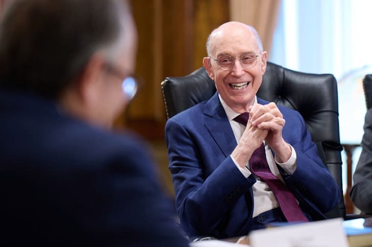 President Henry B. Eyring of the First Presidency smiles during a meeting, representing Church leadership and global outreach in Church news April 2026