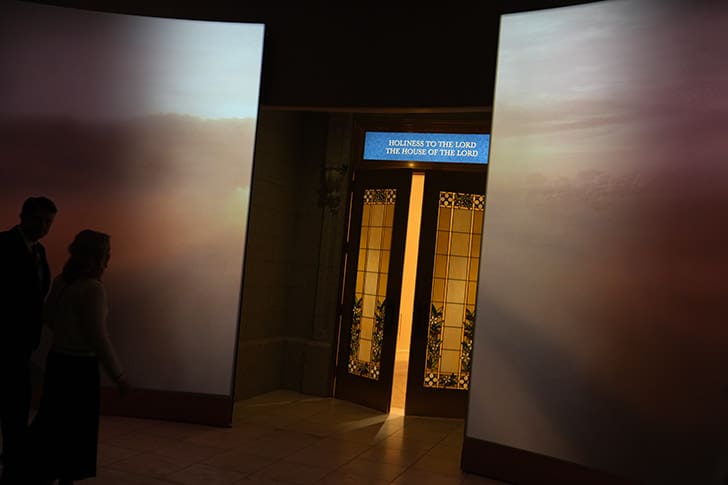 Visitors approach symbolic temple doors inside the Temple Square Visitors’ Center, representing the experience of entering an LDS temple.