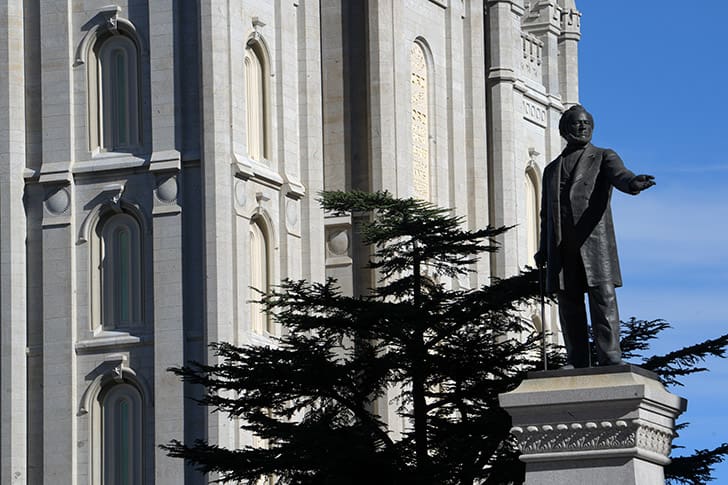 Statue of Brigham Young at Temple Square with the Salt Lake Temple in the background, representing the pioneer heritage of the site.