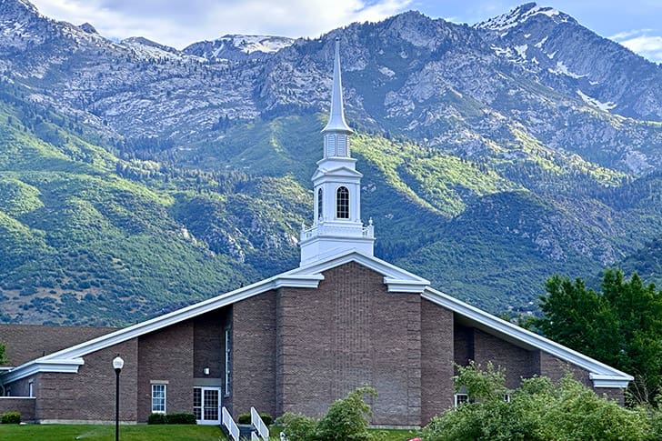A Latter-day Saint chapel set against mountains, representing local Church units included in the statistical report and global Church growth.