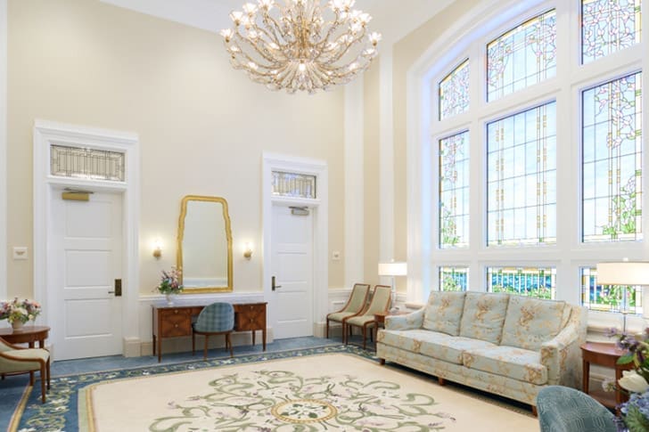 Elegant interior of a temple with seating, chandelier, and stained glass, reflecting sacred design and worship.