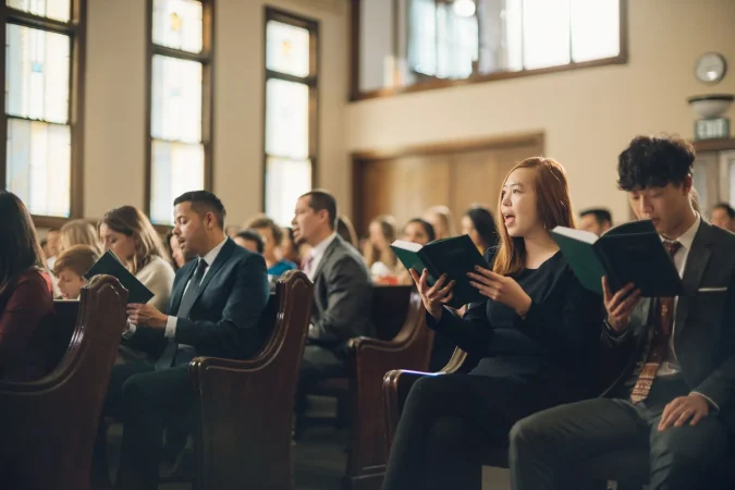 Latter-day Saints gathered in a chapel singing hymns during worship services, reflecting faith and devotion to Jesus Christ.