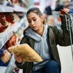 Woman shopping for food storage and emergency food supply items in a grocery store during rising food prices and emergency preparedness planning
