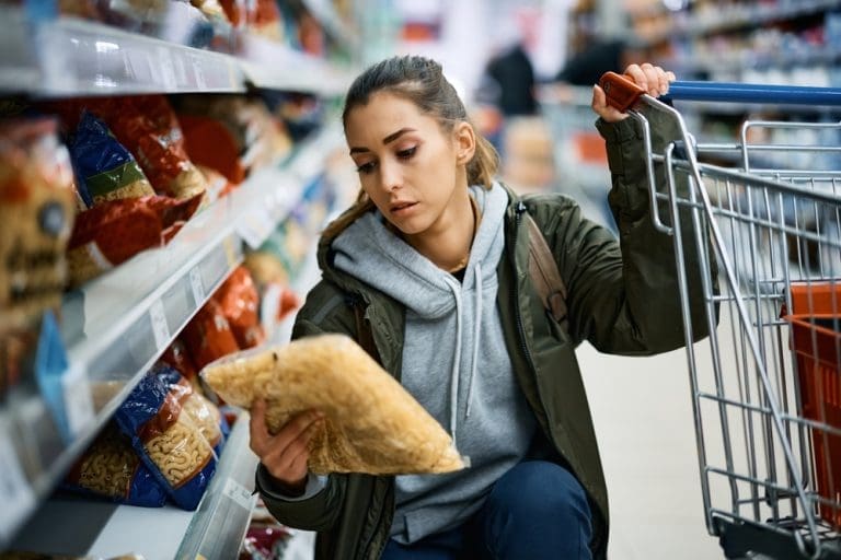 Woman shopping for food storage and emergency food supply items in a grocery store during rising food prices and emergency preparedness planning