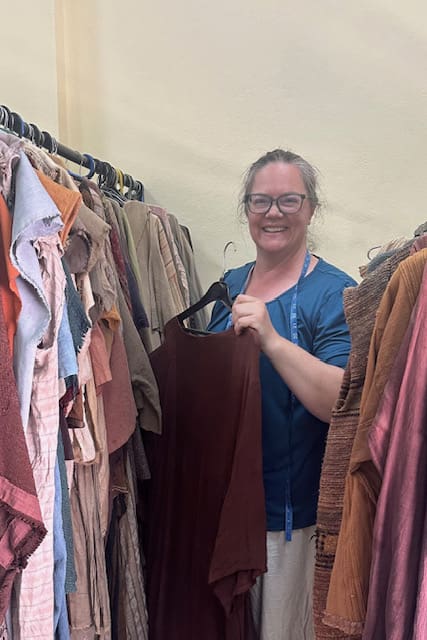 Costume designer Sonya Harris stands among racks of handcrafted garments created for The Ten Virgins, showcasing the scale of the wardrobe effort behind the production.